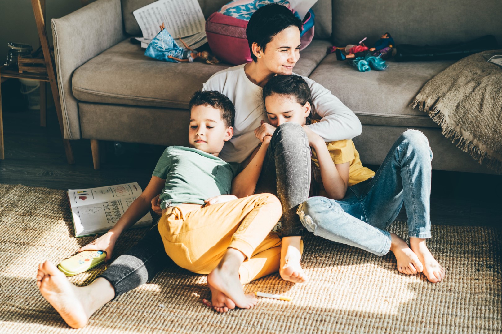 A mom sitting on the floor with two children curled up in her lap all happy